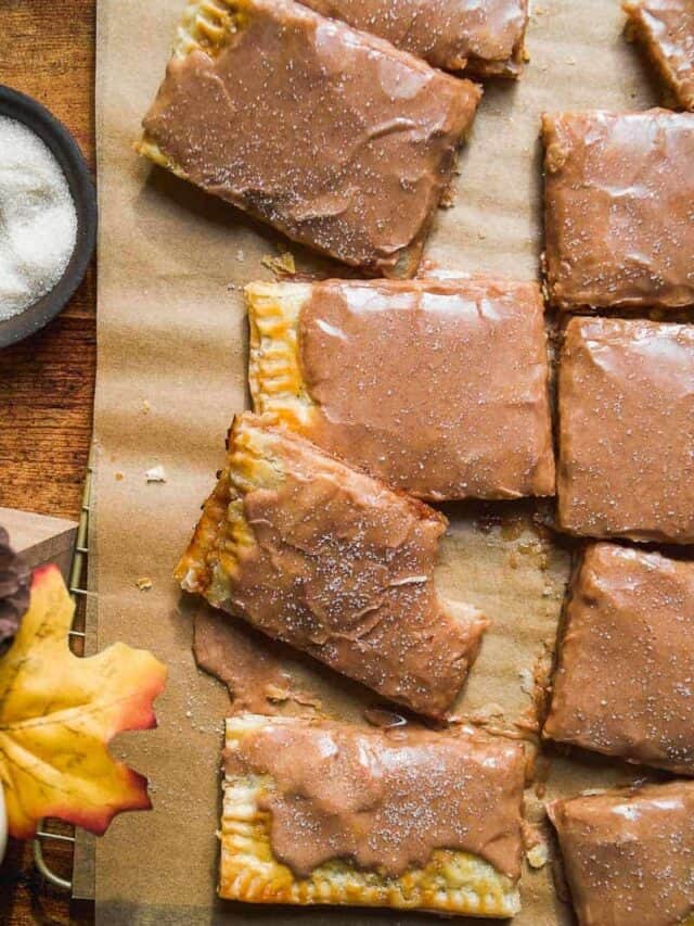 Overhead image of apple pop tarts cut into rectangles on parchment paper.