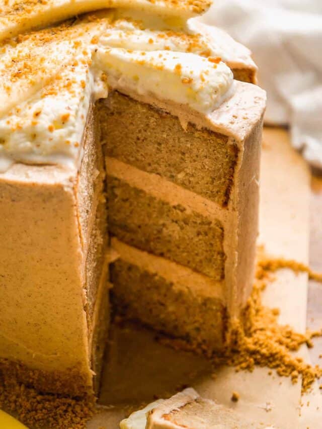 Banana cake with whipped cream on top and a slice about to be removed.