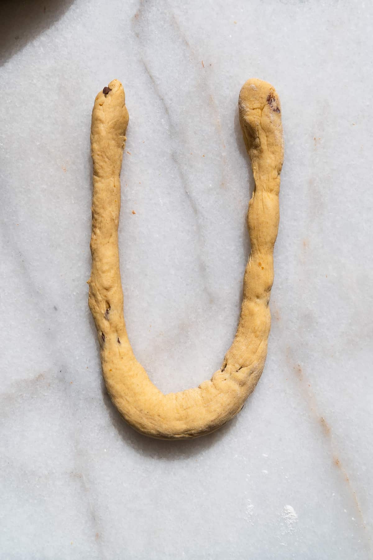 Pumpkin soft pretzel dough in a U shape.