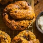 Pumpkin soft pretzels with chocolate chips on a wire rack.