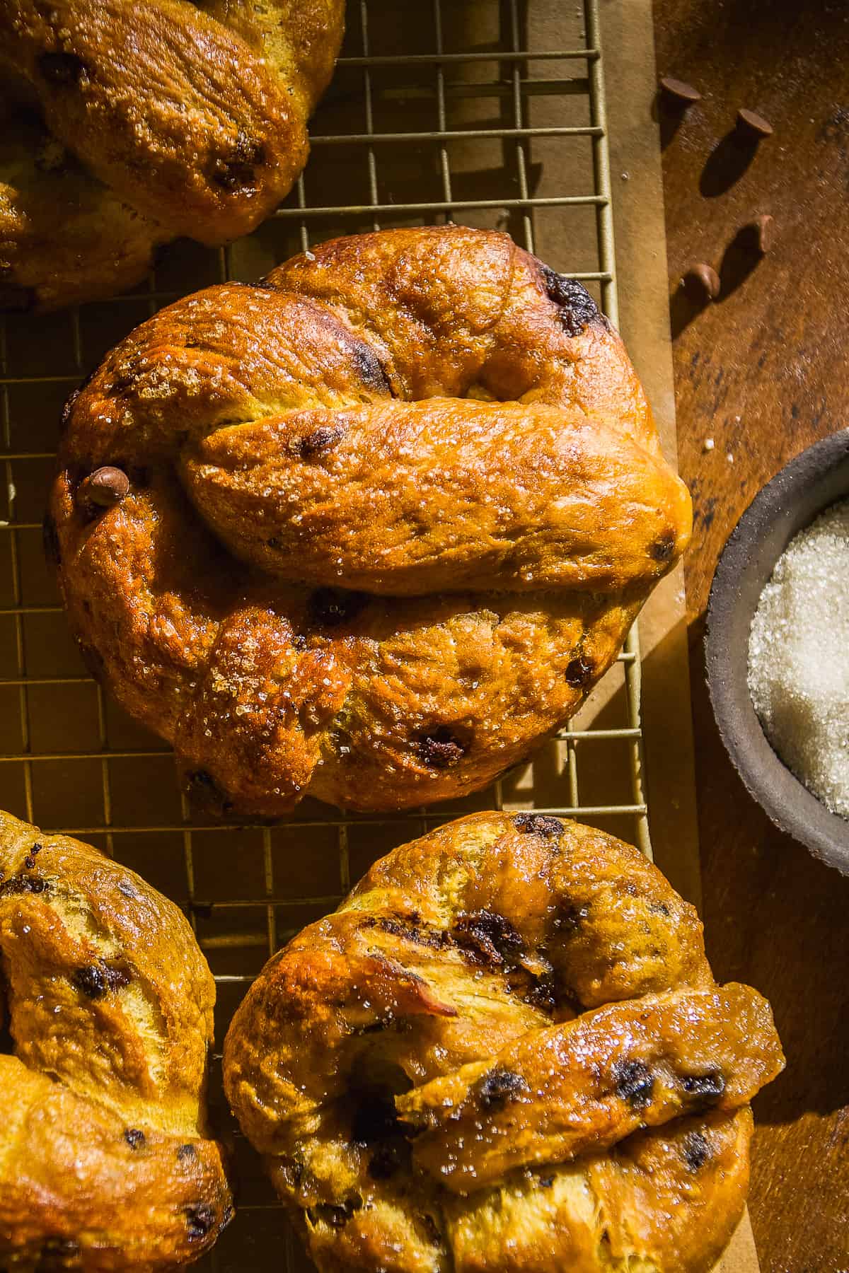 Pumpkin soft pretzels with chocolate chips on a wire rack.