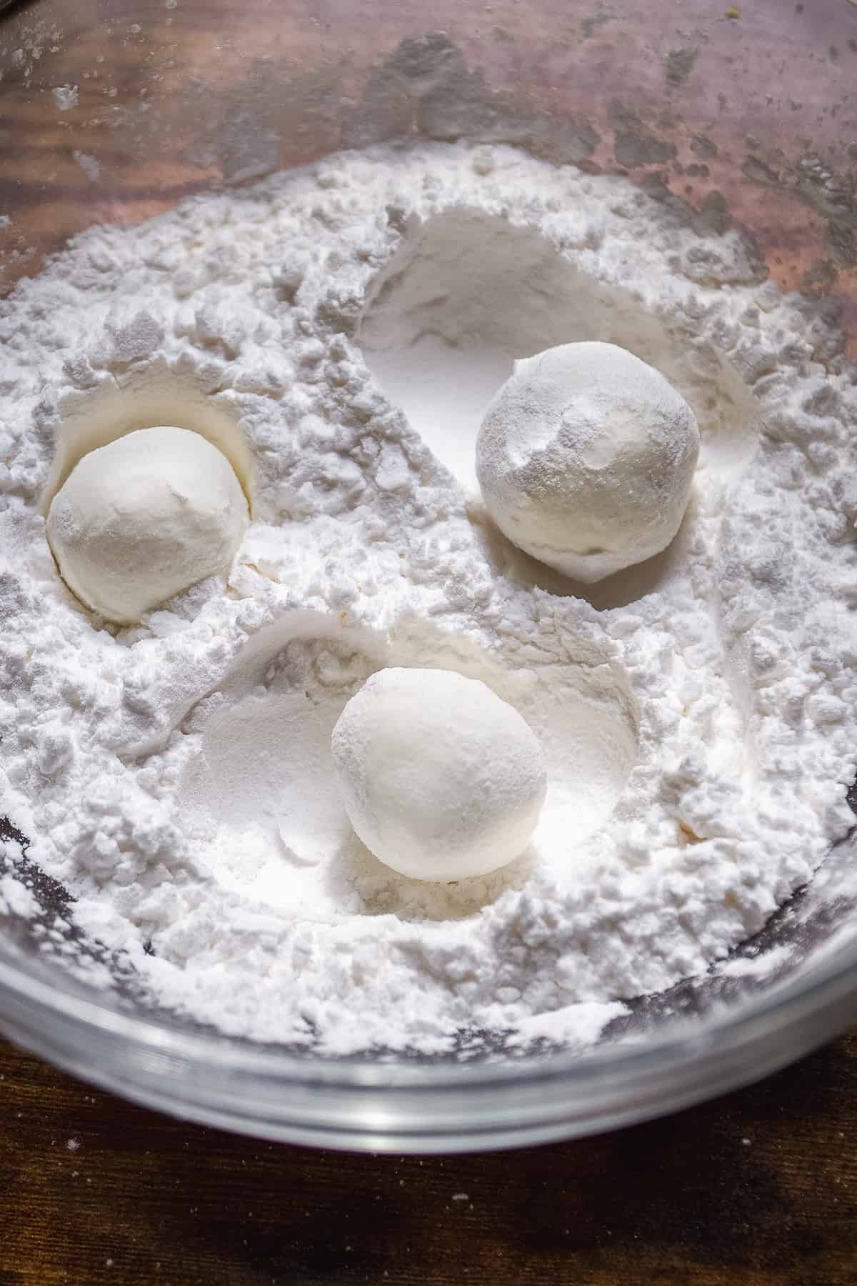 Goat cheese balls being tossed in flour.