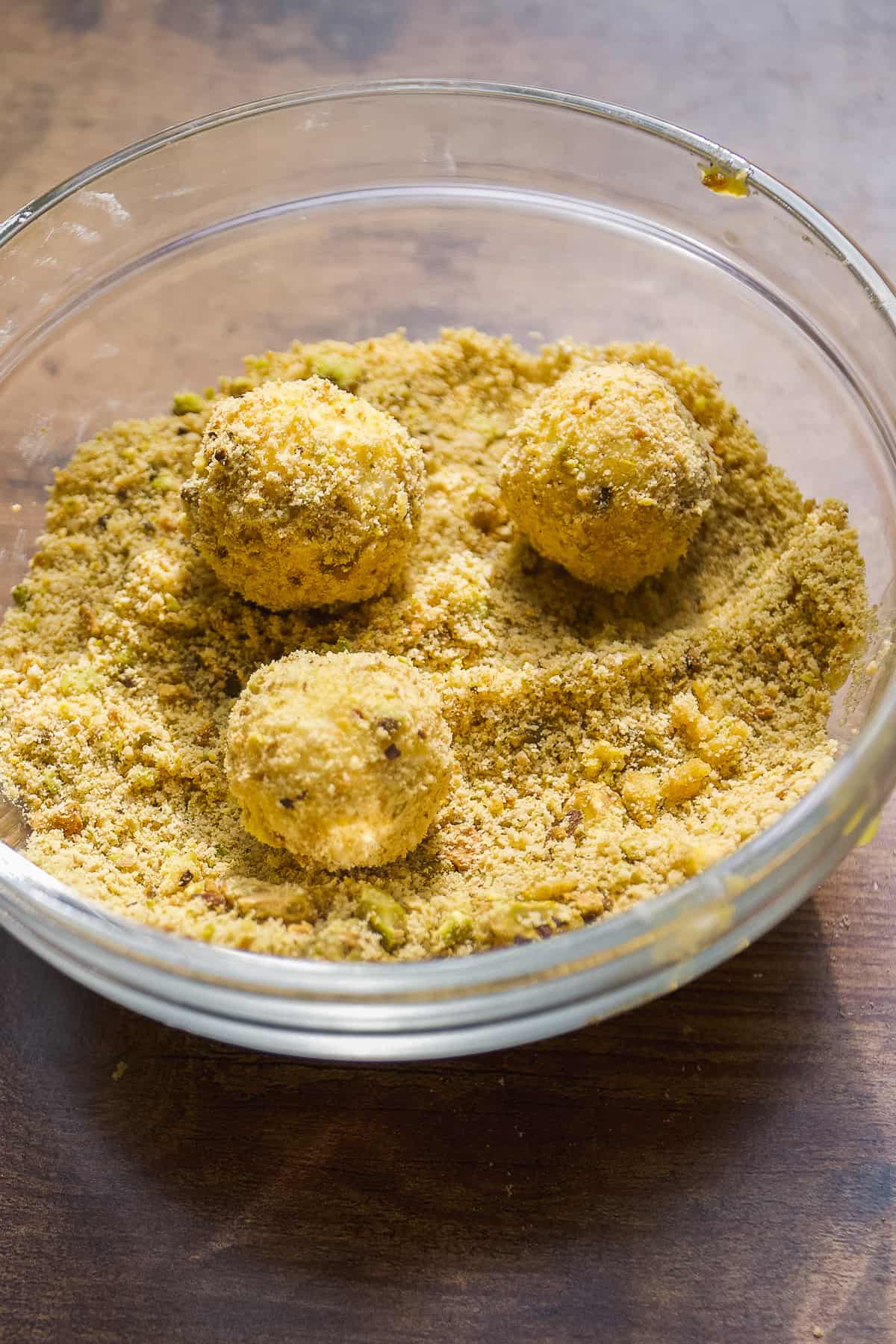 Goat cheese balls being coated in breading.