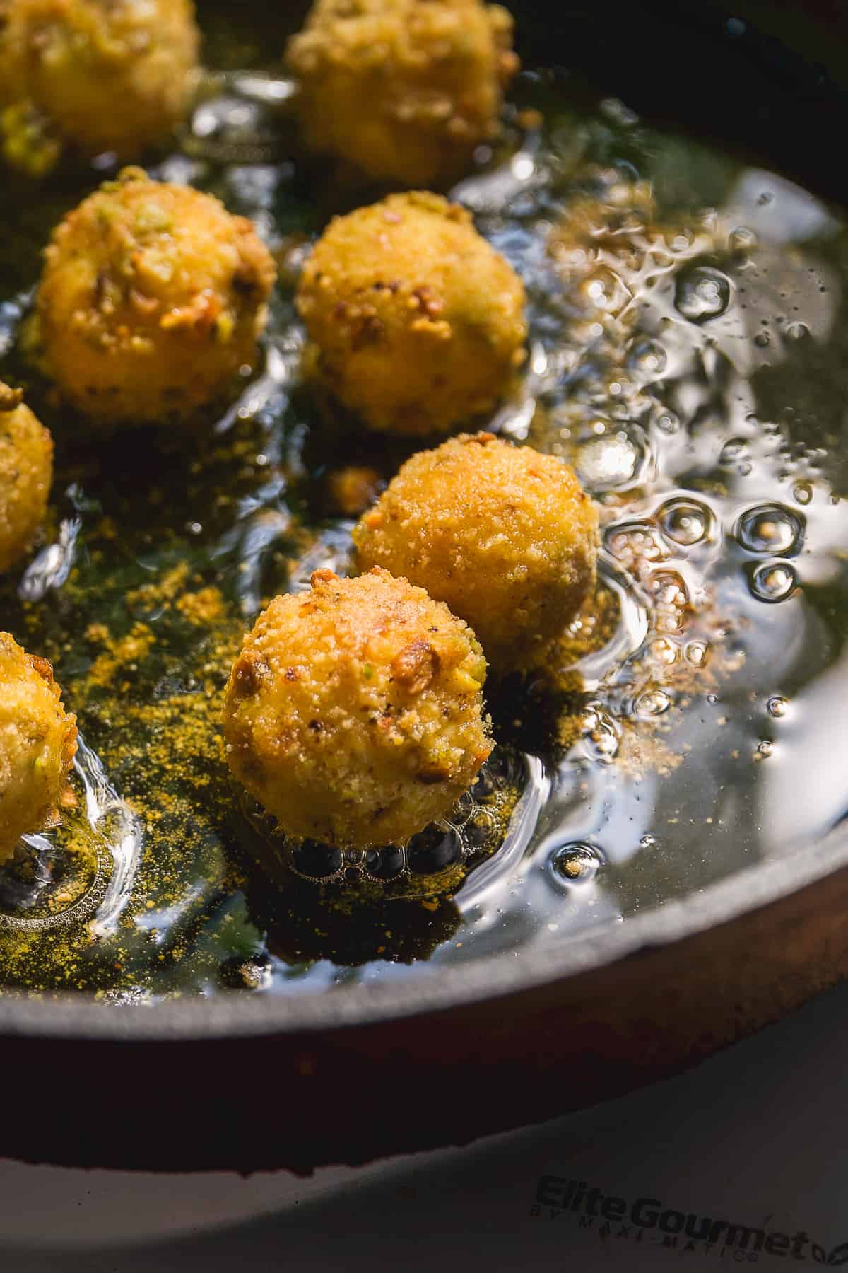 Goat cheese balls being pan fried in a pan.
