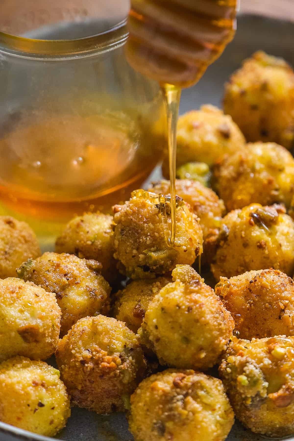 Fried goat cheese balls on a plate with honey drizzled on top.