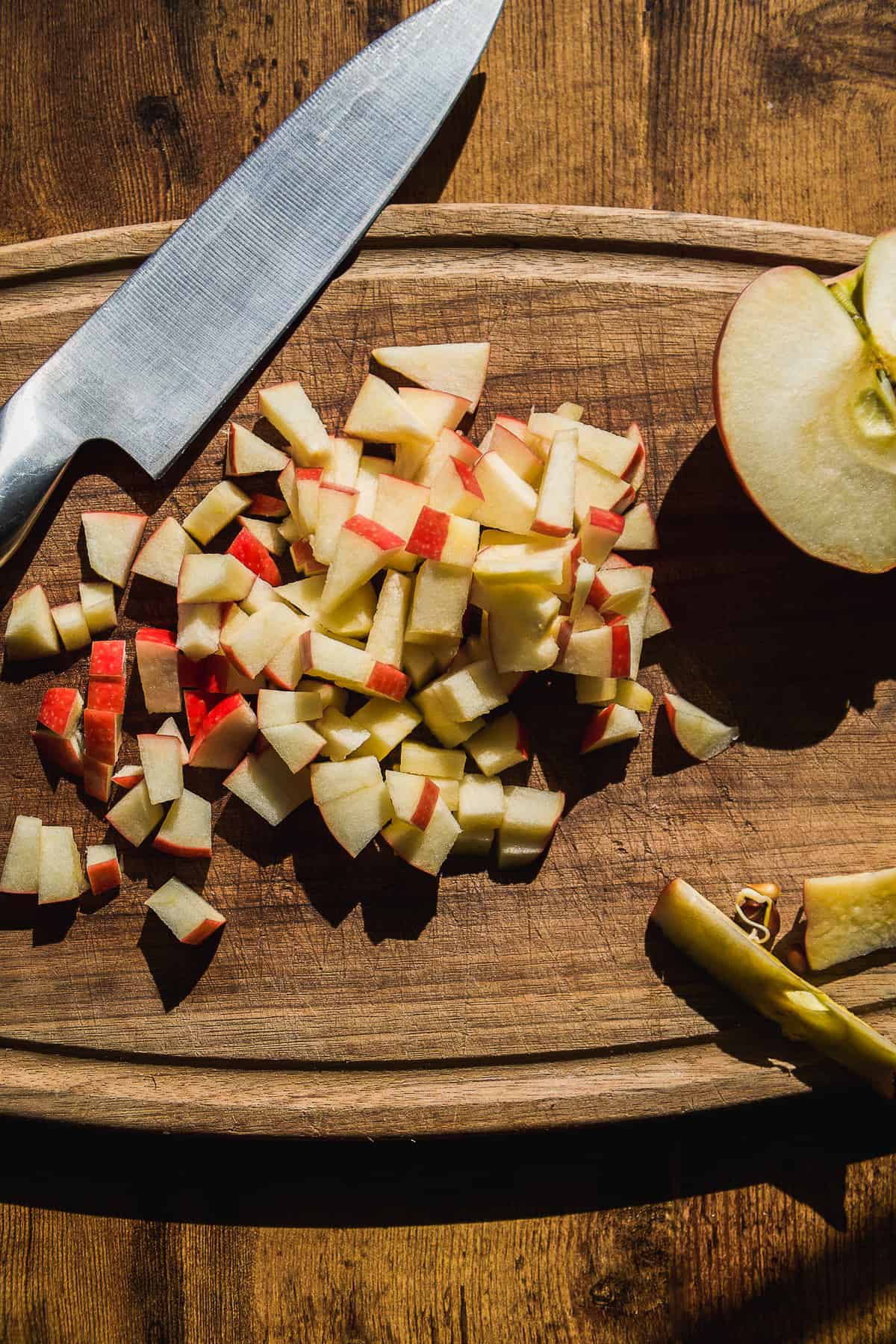 Apples diced into pieces on a wooden cutting board.