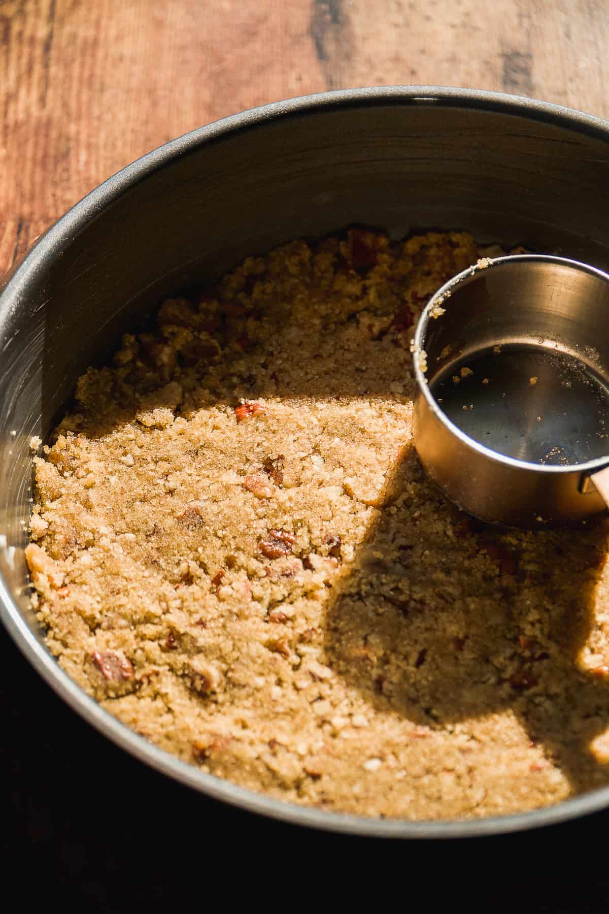 Pecan brown sugar mixture being packed into a cake pan.