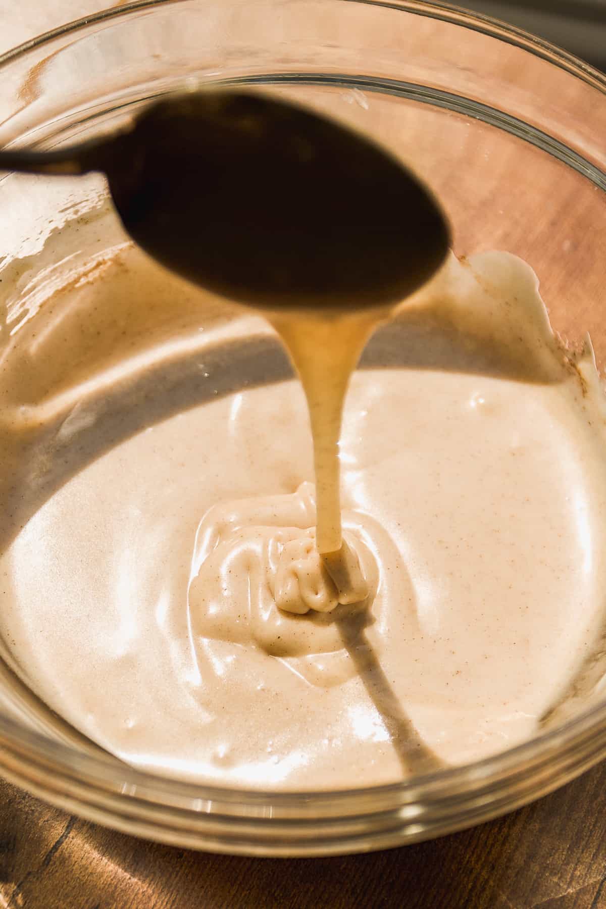 Cinnamon cream cheese icing in a glass bowl.