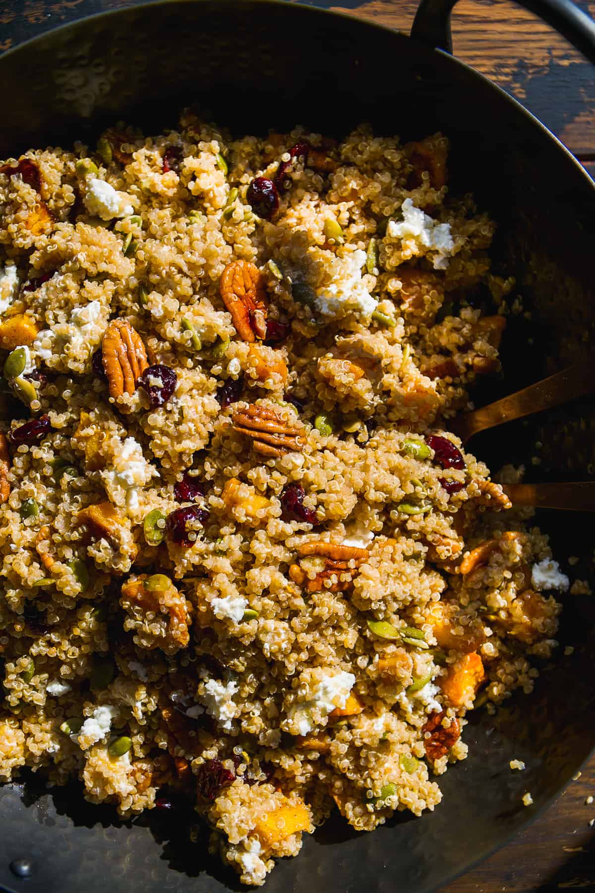 Overhead view of pumpkin quinoa salad with goat cheese in a black bowl.
