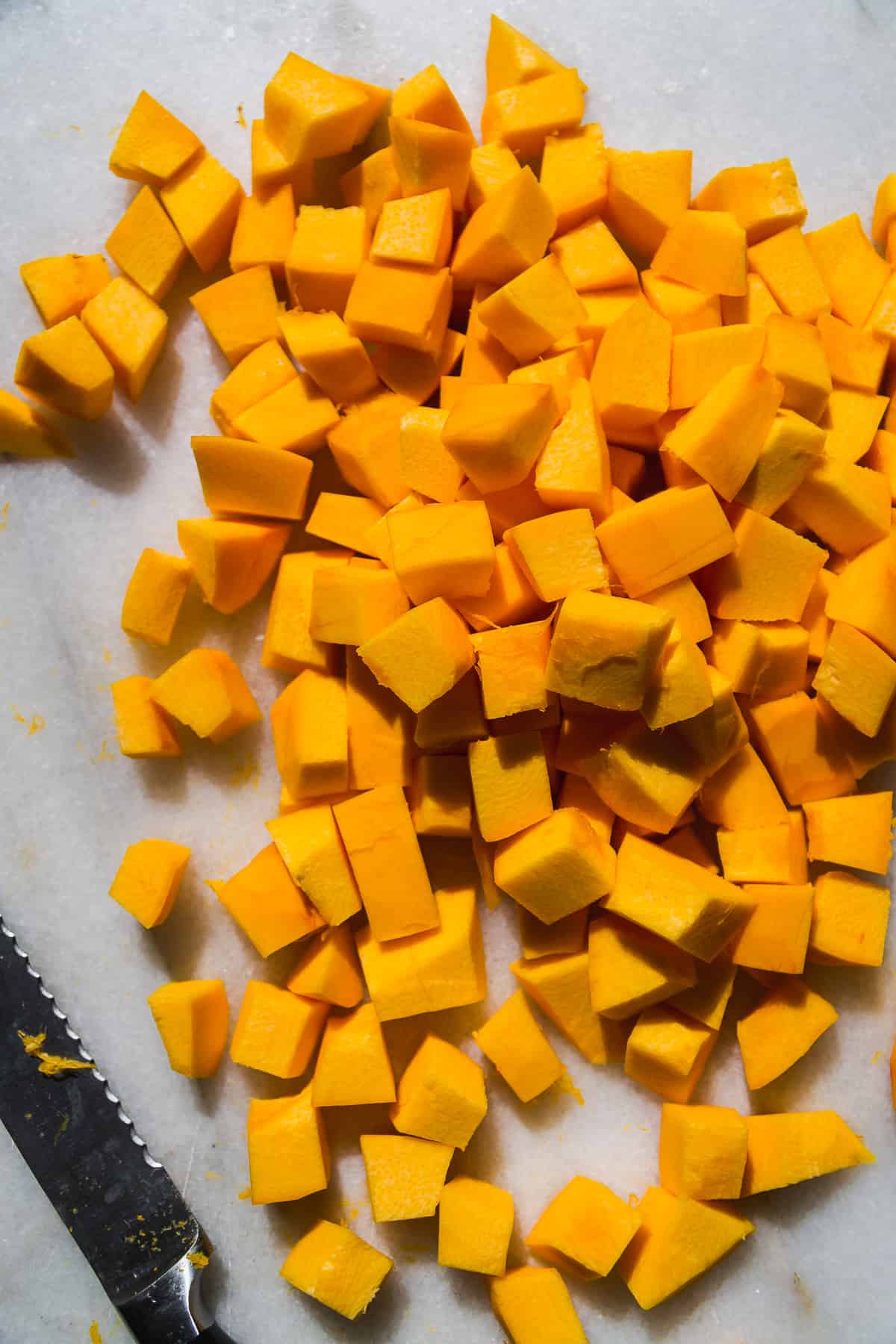 Pumpkin cut into cubes on a marble surface.