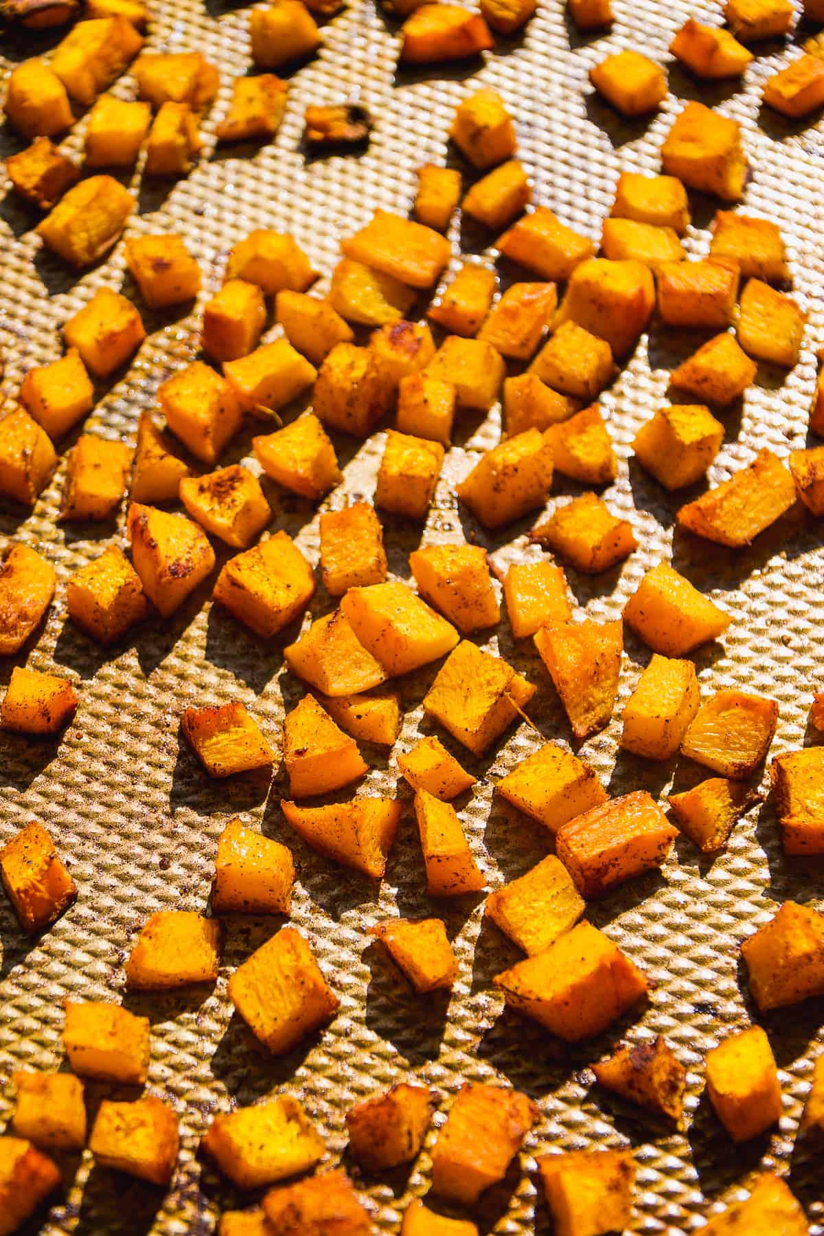 Roasted pumpkin cubes on a baking sheet.