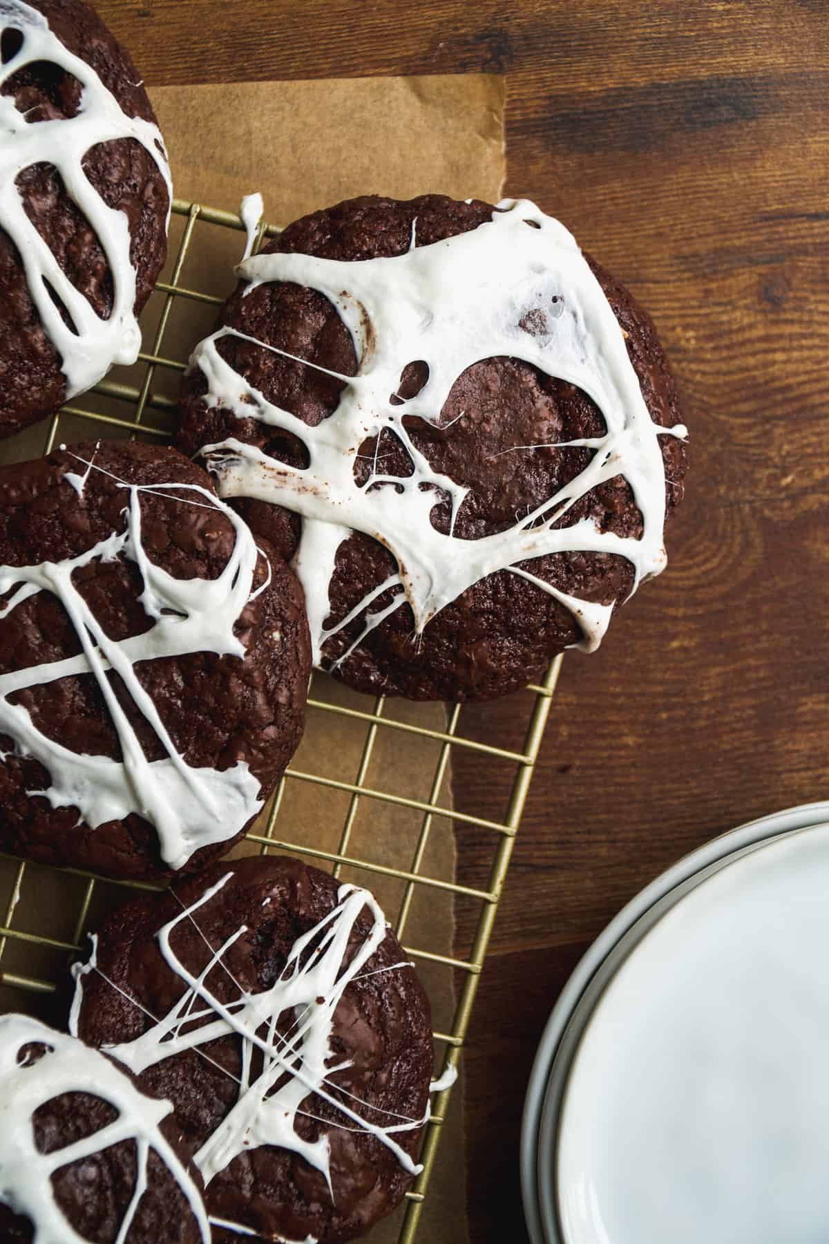 Chocolate spider web cookies on a wire rack.