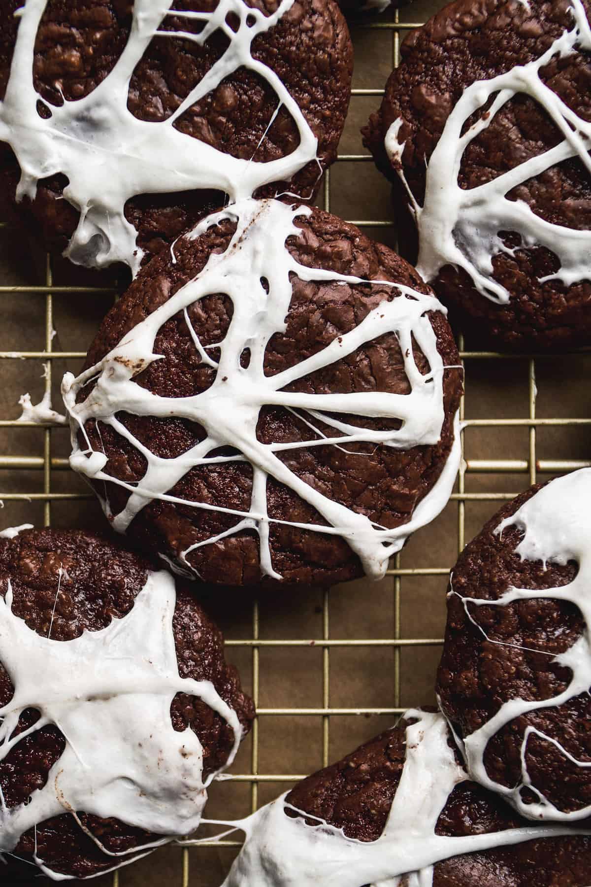 Chocolate spider web cookies on a wire rack.