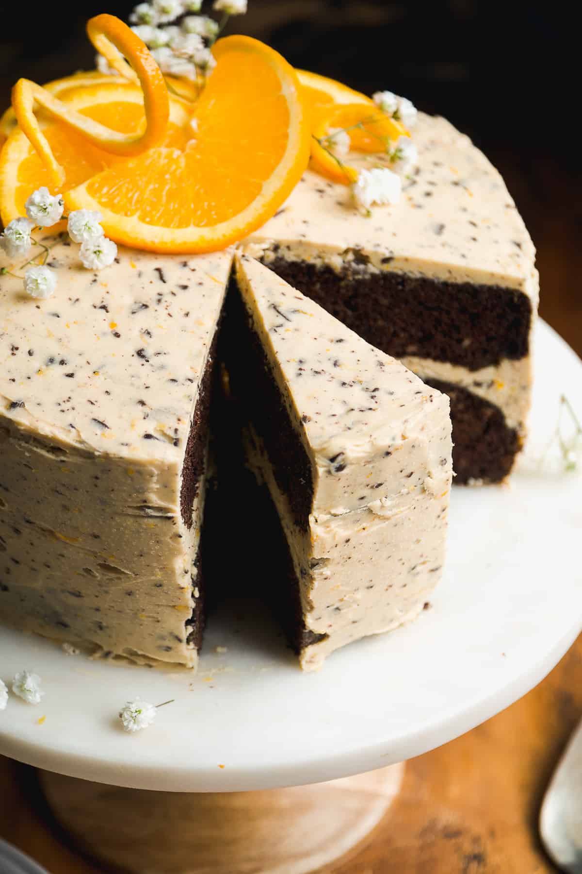 Chocolate orange cake on a stand with a slice cut out of the cake.