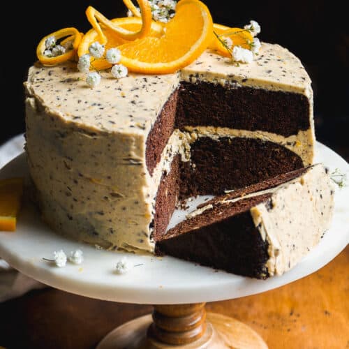 Chocolate orange cake on a cake stand with orange slices on top.