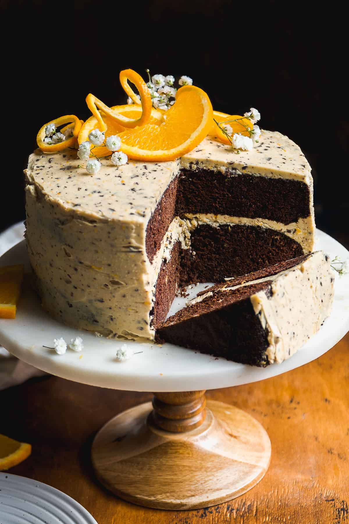 Chocolate orange cake on a cake stand with orange slices on top.