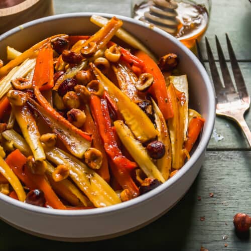 Bowl of honey roasted carrots and parsnips with hazelnuts.