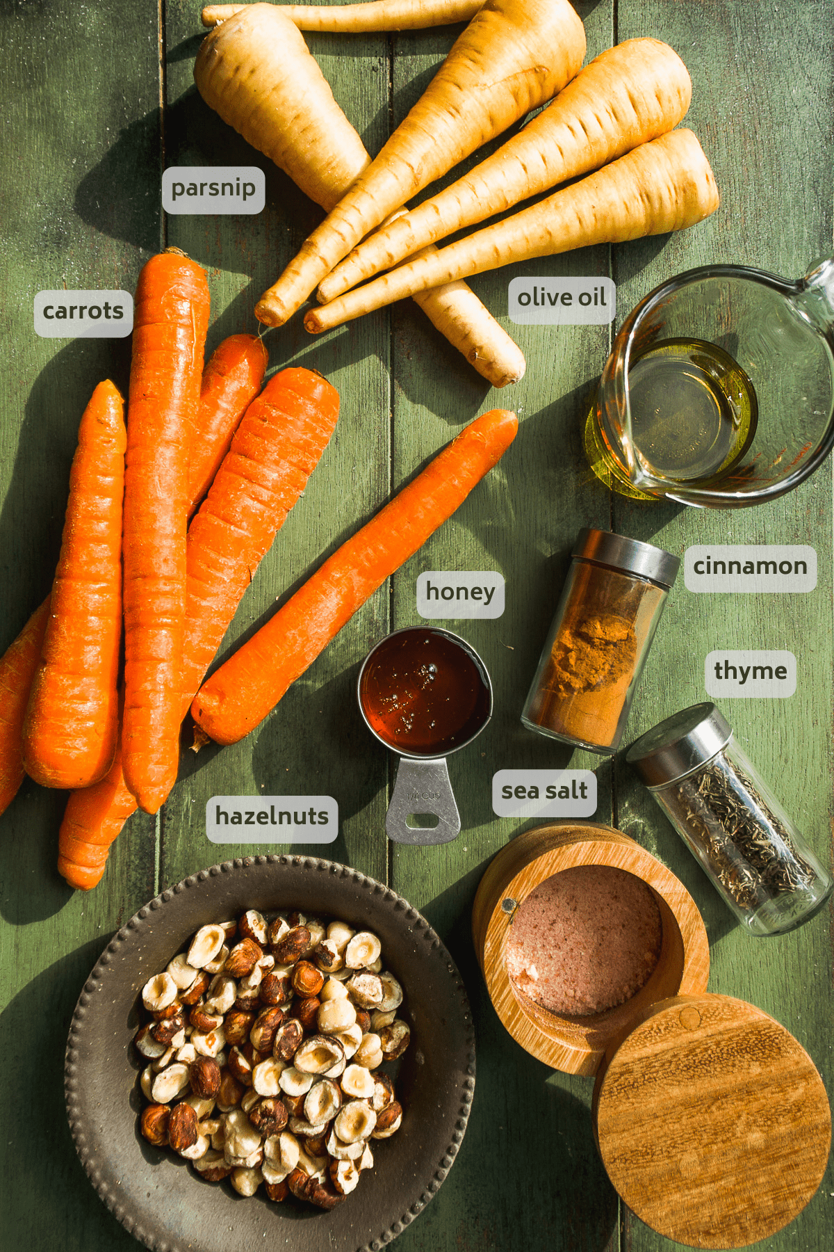 Honey roasted carrots and parsnips ingredients on a green surface.