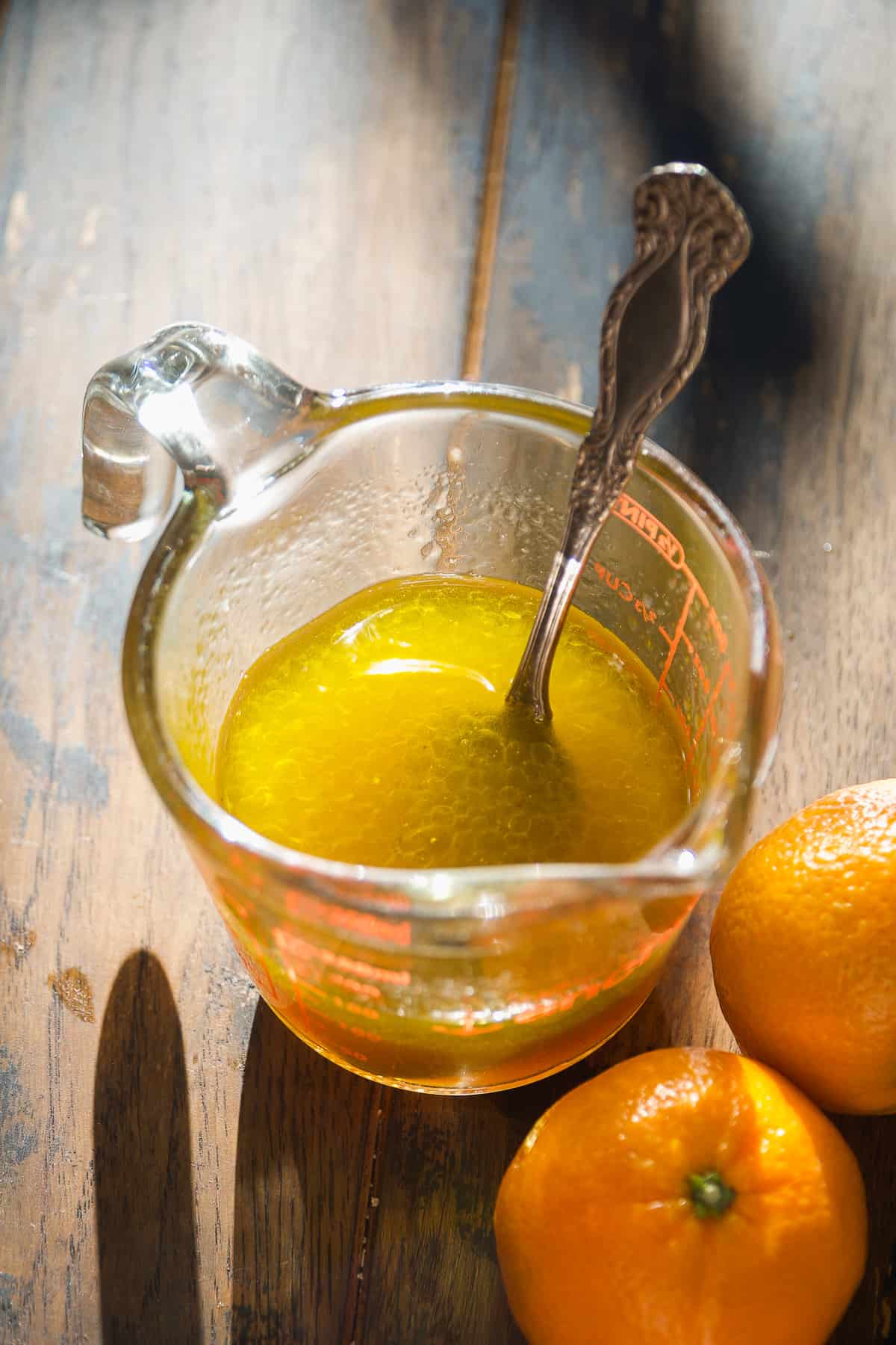 Mandarin orange salad dressing in a glass on a wooden surface.