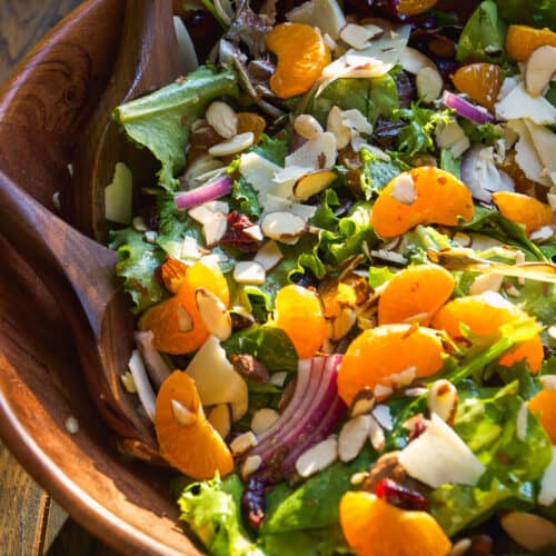Salad with mandarin oranges tossed in a wooden bowl.