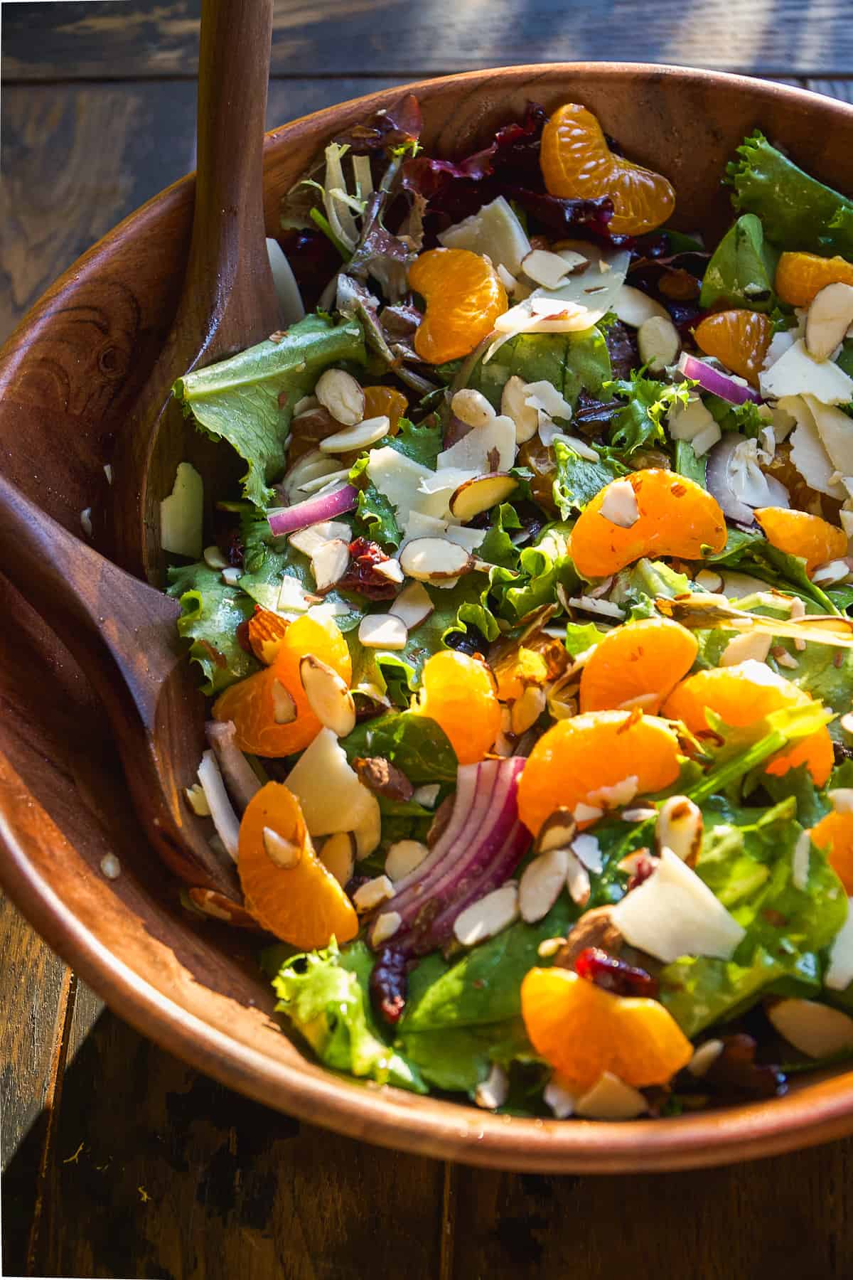 Salad with mandarin oranges tossed in a wooden bowl.