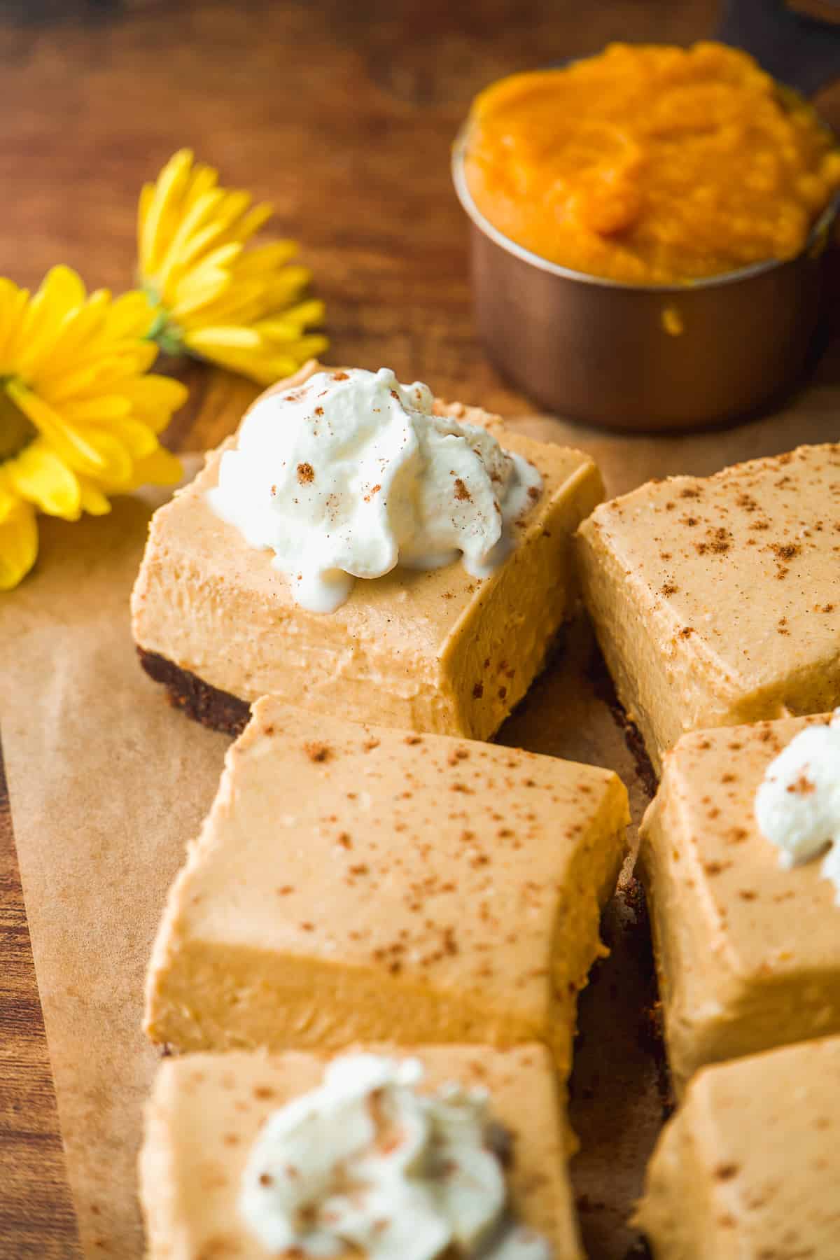 Square pumpkin cheesecake bars with whipped cream on top.