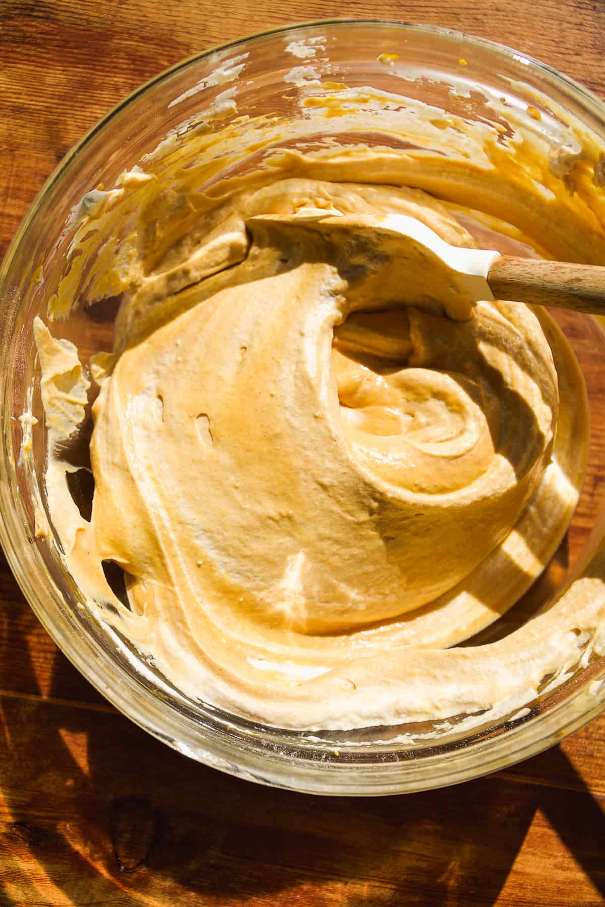 Pumpkin cheesecake batter mixed in a bowl with a spatula.