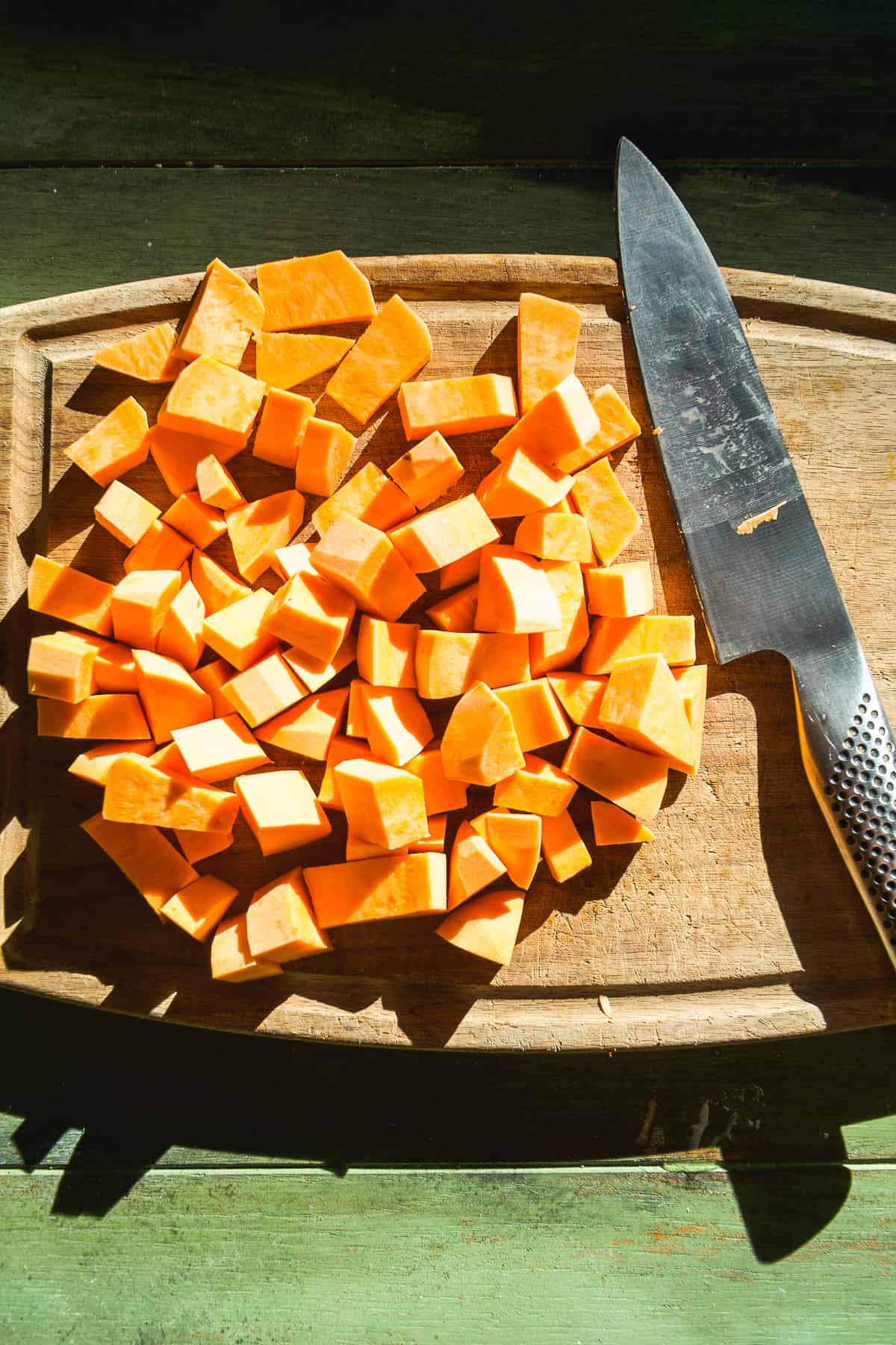 Sweet potato cut into cubs on a wooden board.