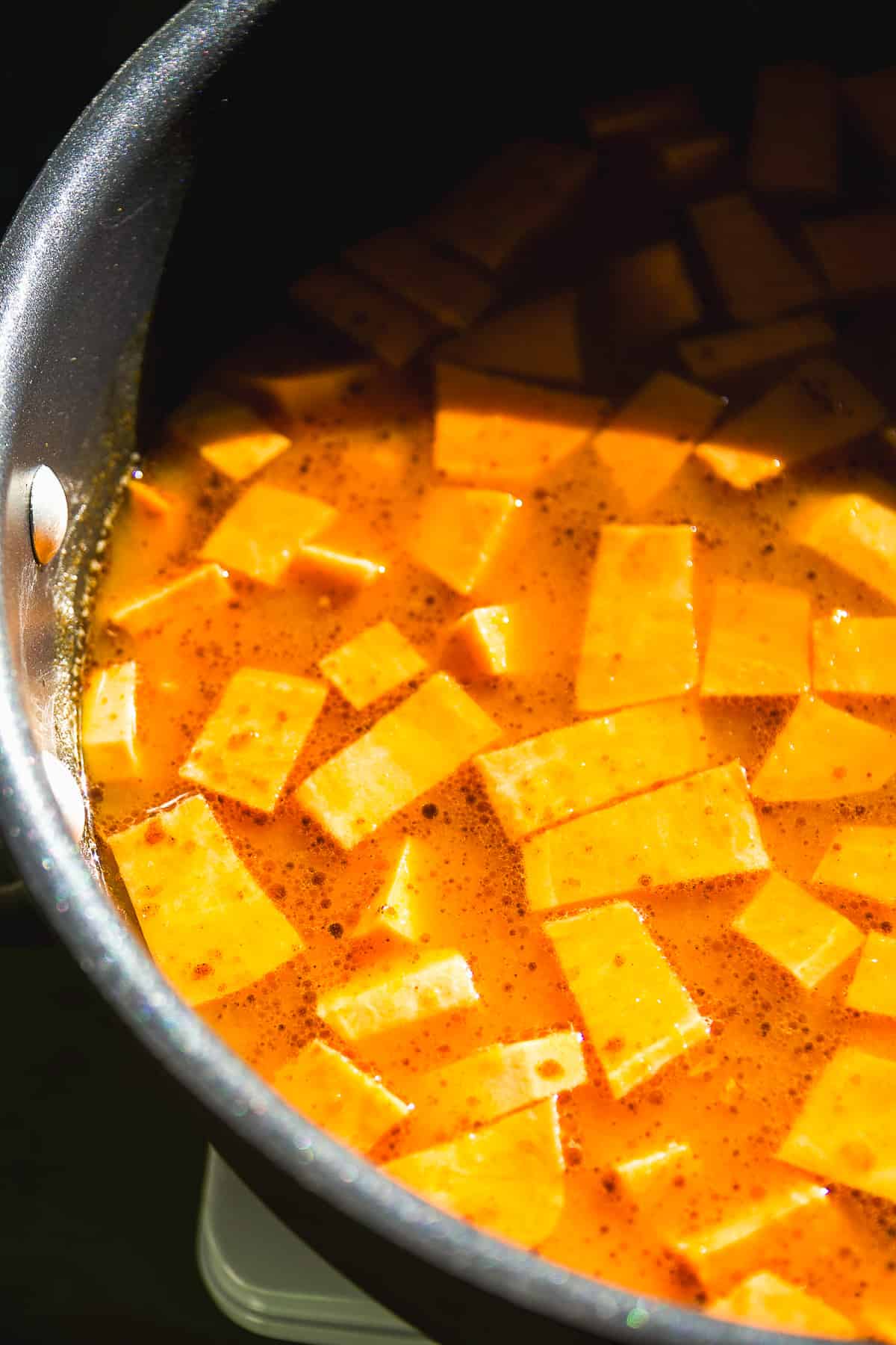 Sweet potato pumpkin soup simmering in a pot.