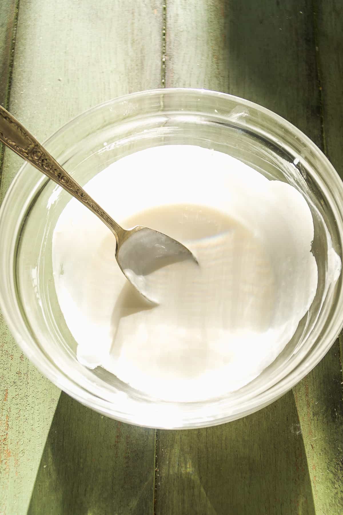 Goat cheese cream in a glass bowl on green surface.