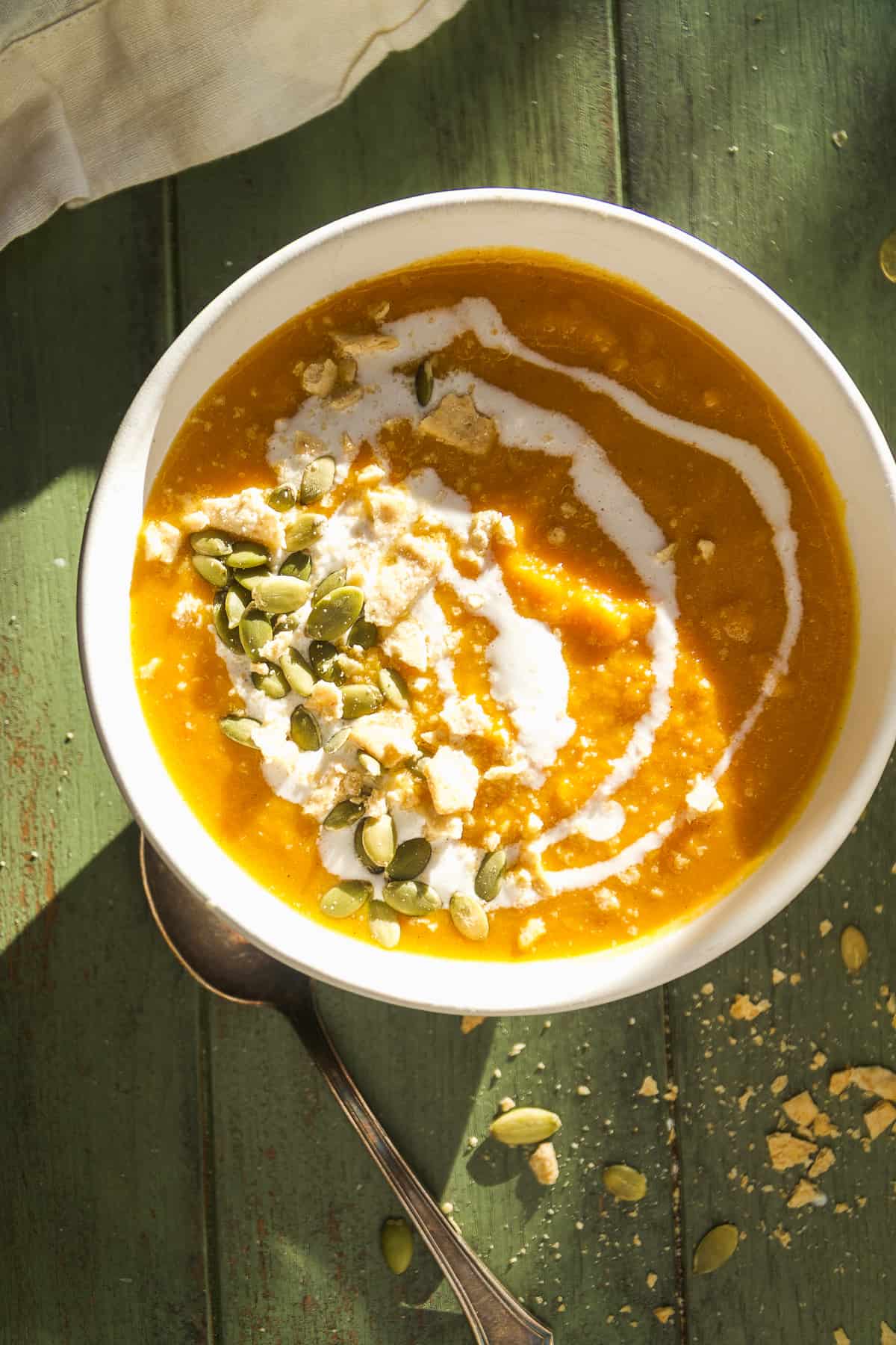 Bowl of pumpkin sweet potato soup with seeds and crackers on top.