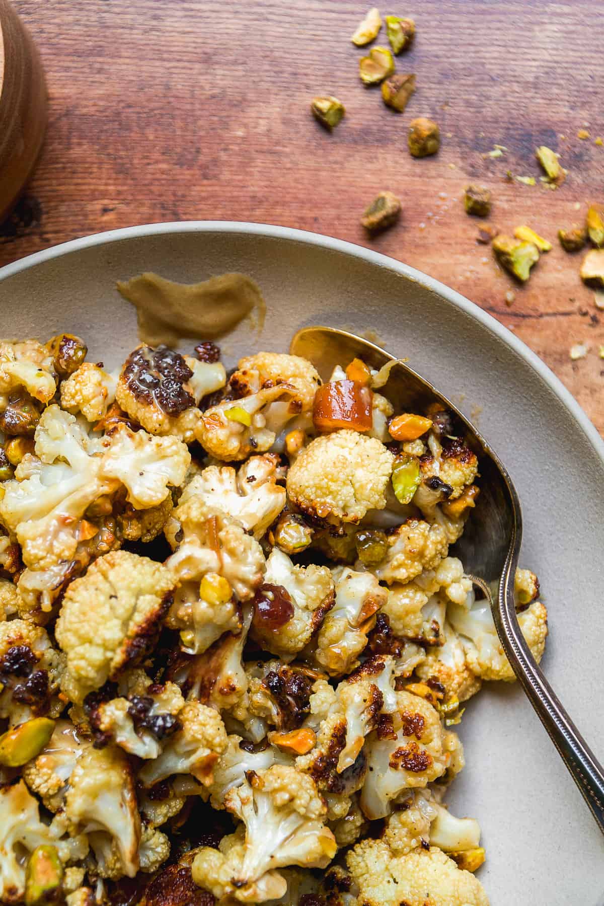 Tahini roasted cauliflower on a platter with dates and pistachios.