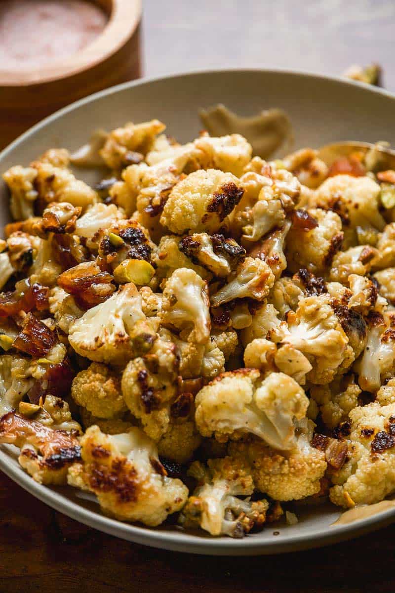 Tahini cauliflower with pistachios and dates on a platter.