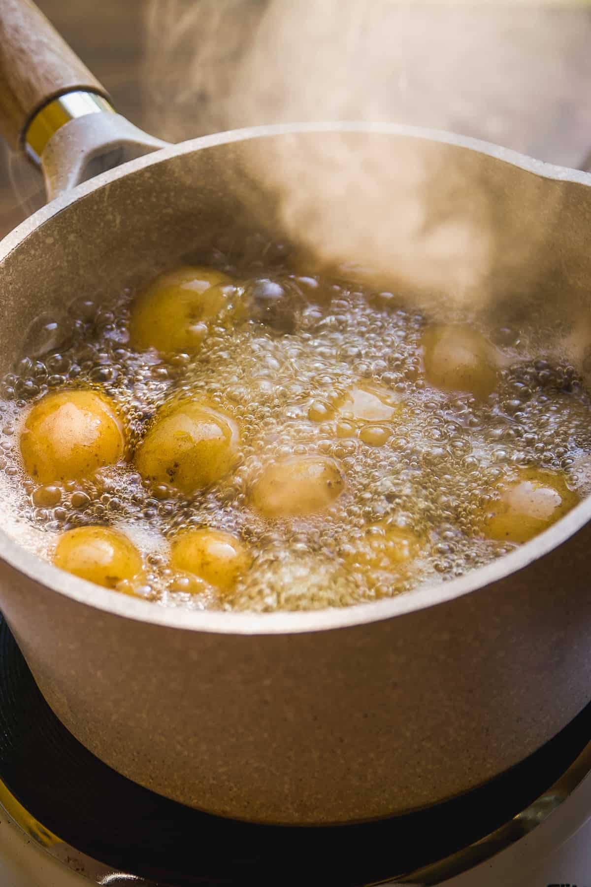 Fingerling potatoes boiling in a pot of water.