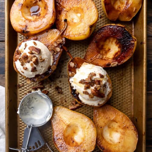 Caramelized pears on a baking pan with ice cream on top.