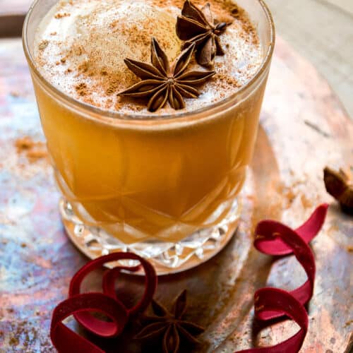 Chai cocktail with star anise on top on a copper platter.