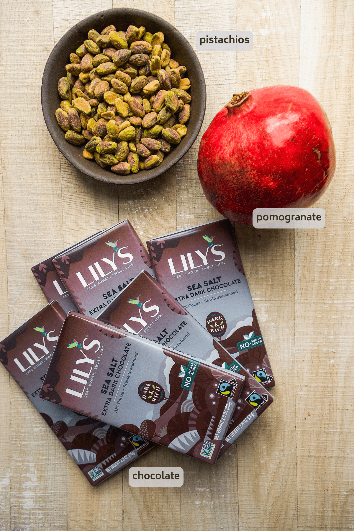 Christmas pomegranate bark ingredients on wooden surface.