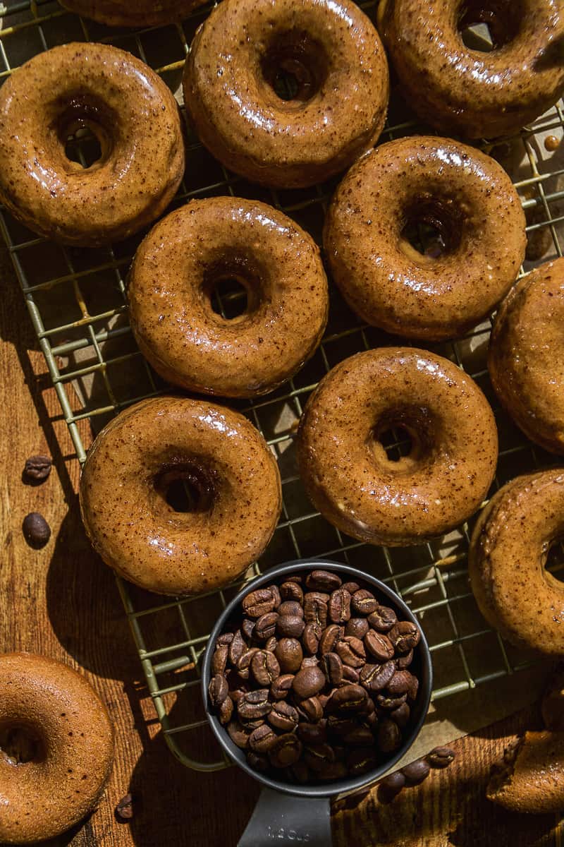 Coffee doughnuts cooling on a wire rack.