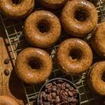 Glazed coffee doughnuts on a wire rack cooling.
