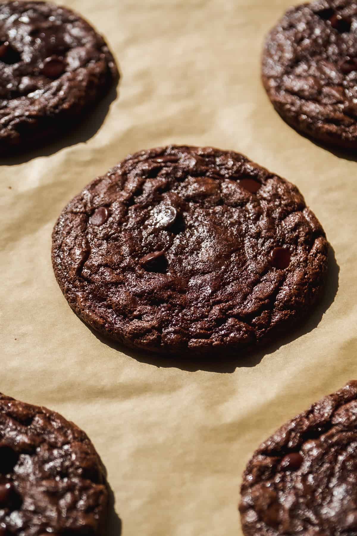 Chocolate brownie crinkle cookie on parchment paper.