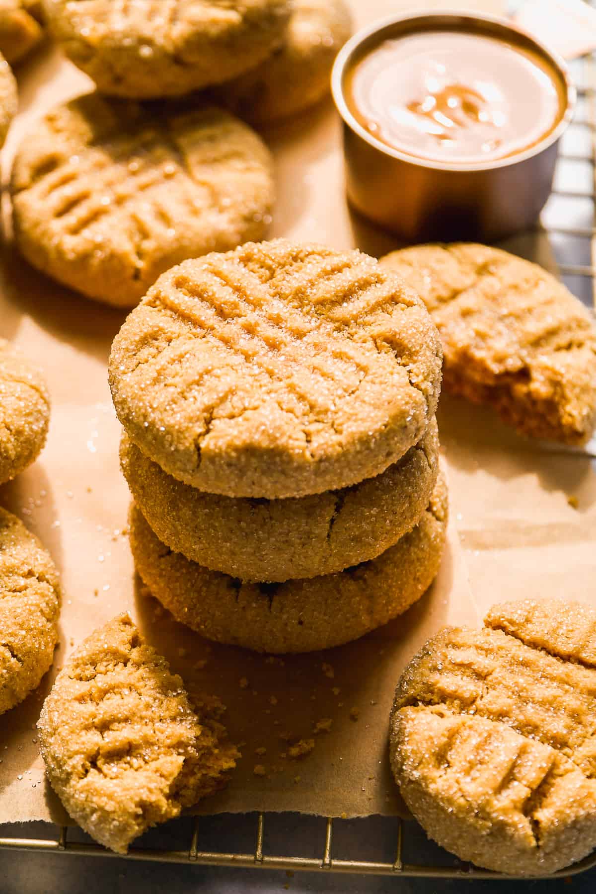 Almond flour peanut butter cookies stacked in a pile on a wire rack.