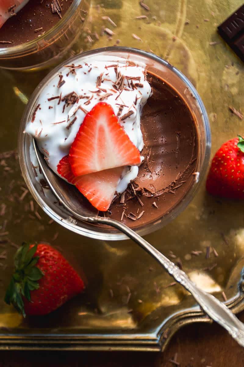 Jar of vegan chocolate mousse with whipped cream and strawberries.