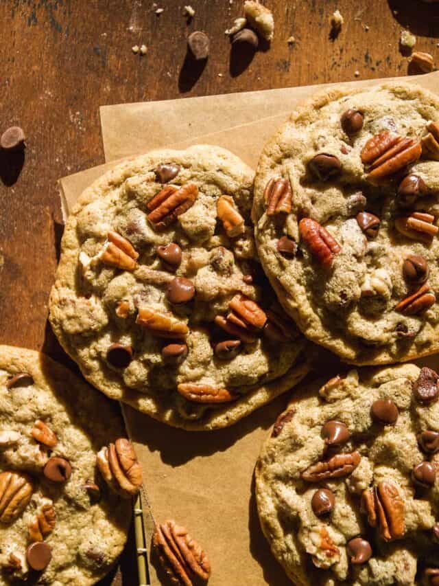 Chocolate chip pecan cookies scattered on a wooden surface.