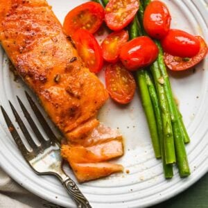 White plate with cast iron salmon with vegetables.