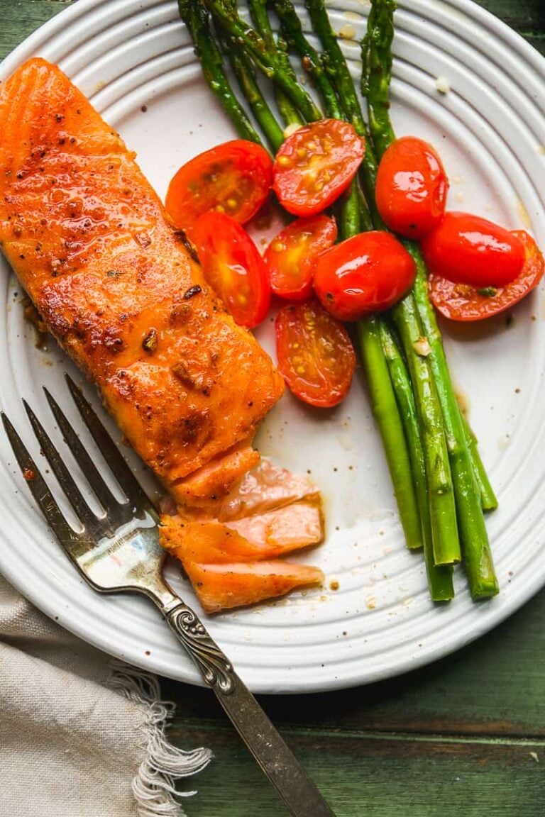 Cast iron salmon on a white plate with vegetables.