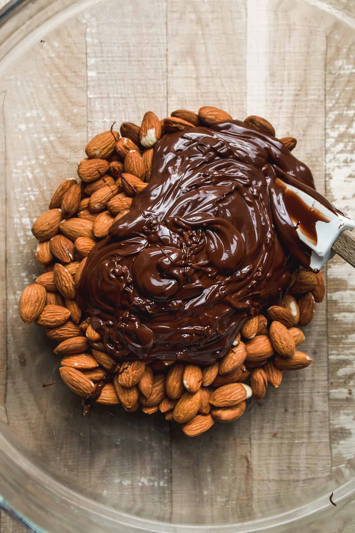 Bowl of almonds about be coated in melted chocolate.