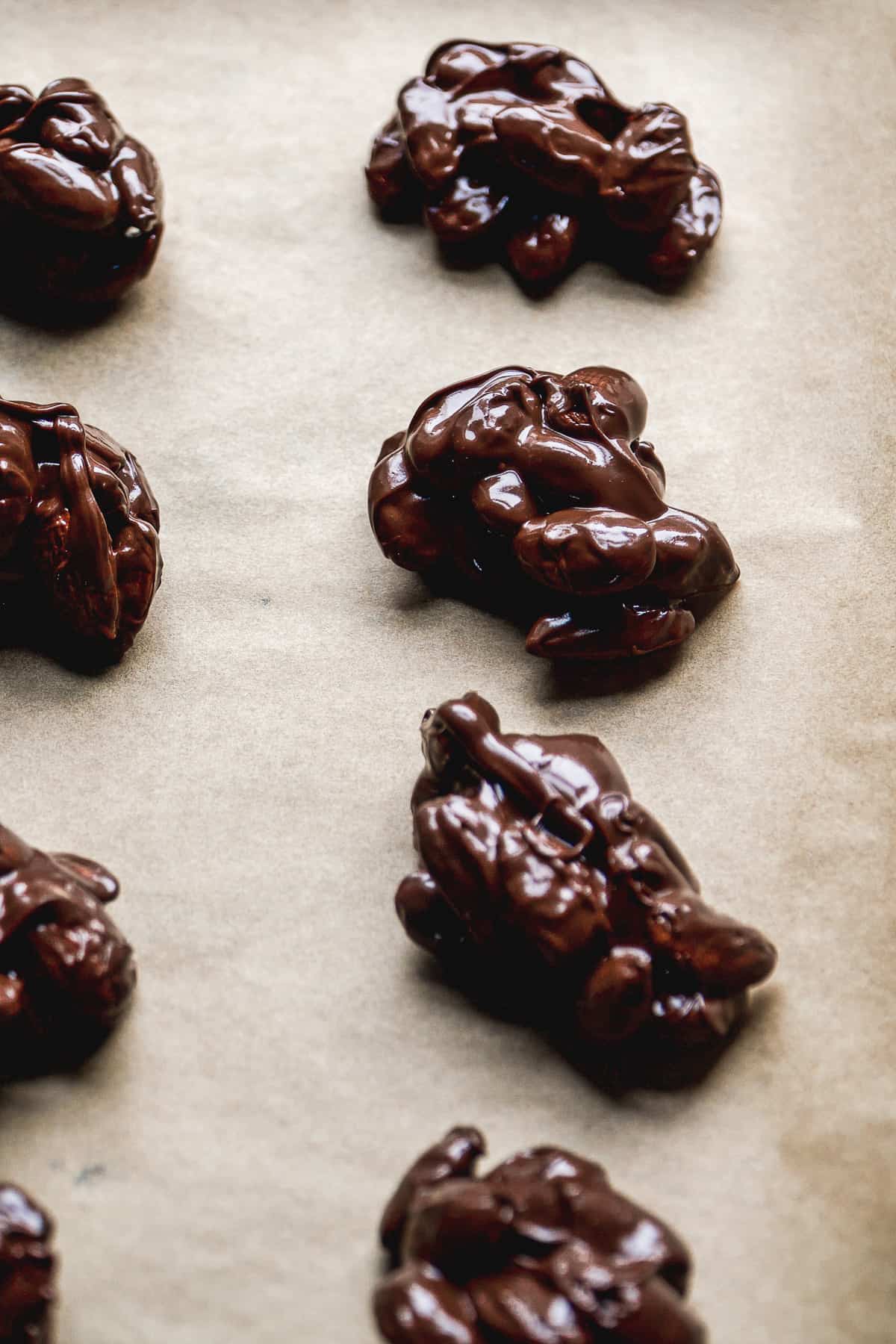 Chocolate almond clusters on a baking sheet setting.