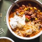 Sweet chili in a white bowl with cheese and yogurt on top.