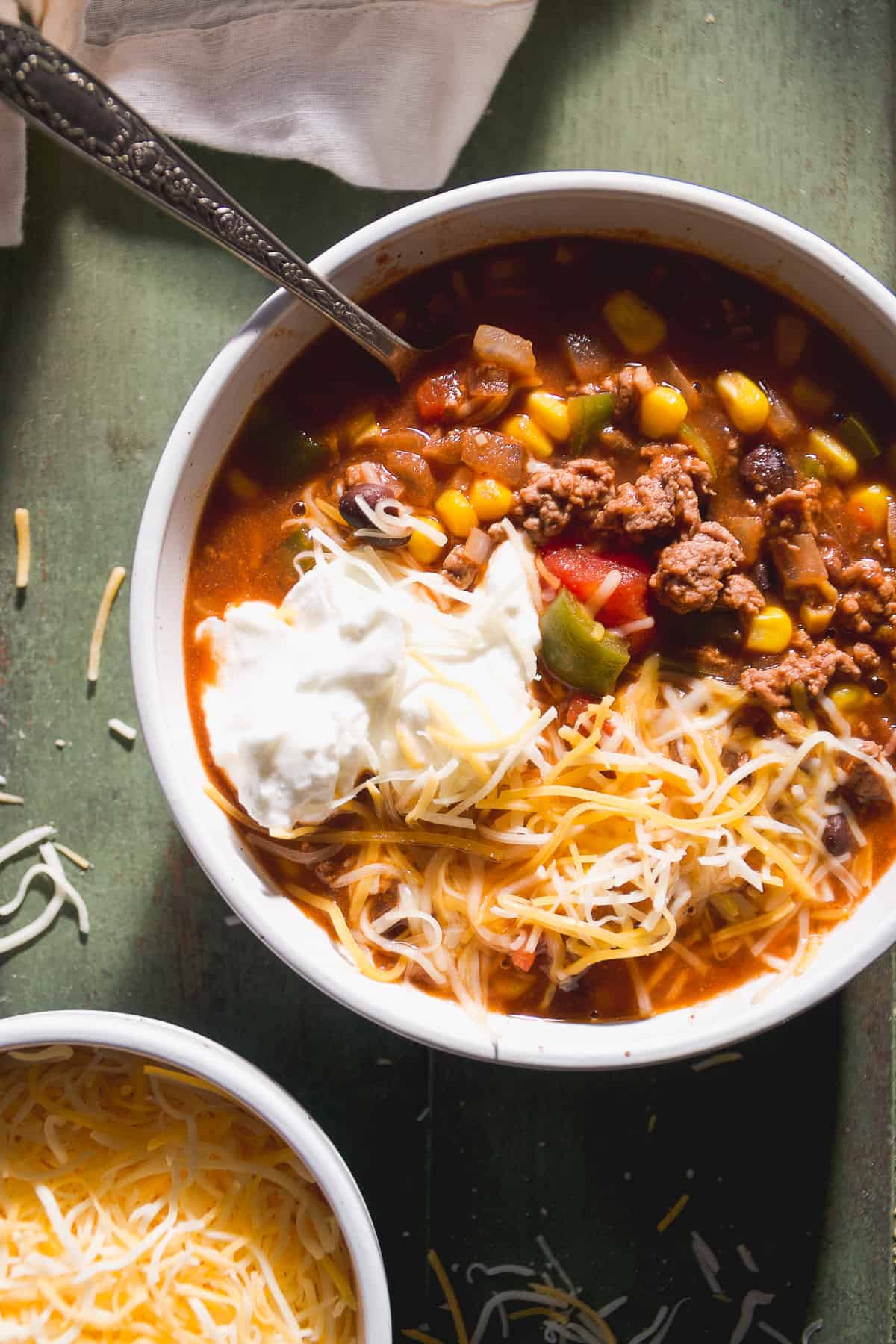 Sweet chili in a white bowl with cheese and yogurt on top.