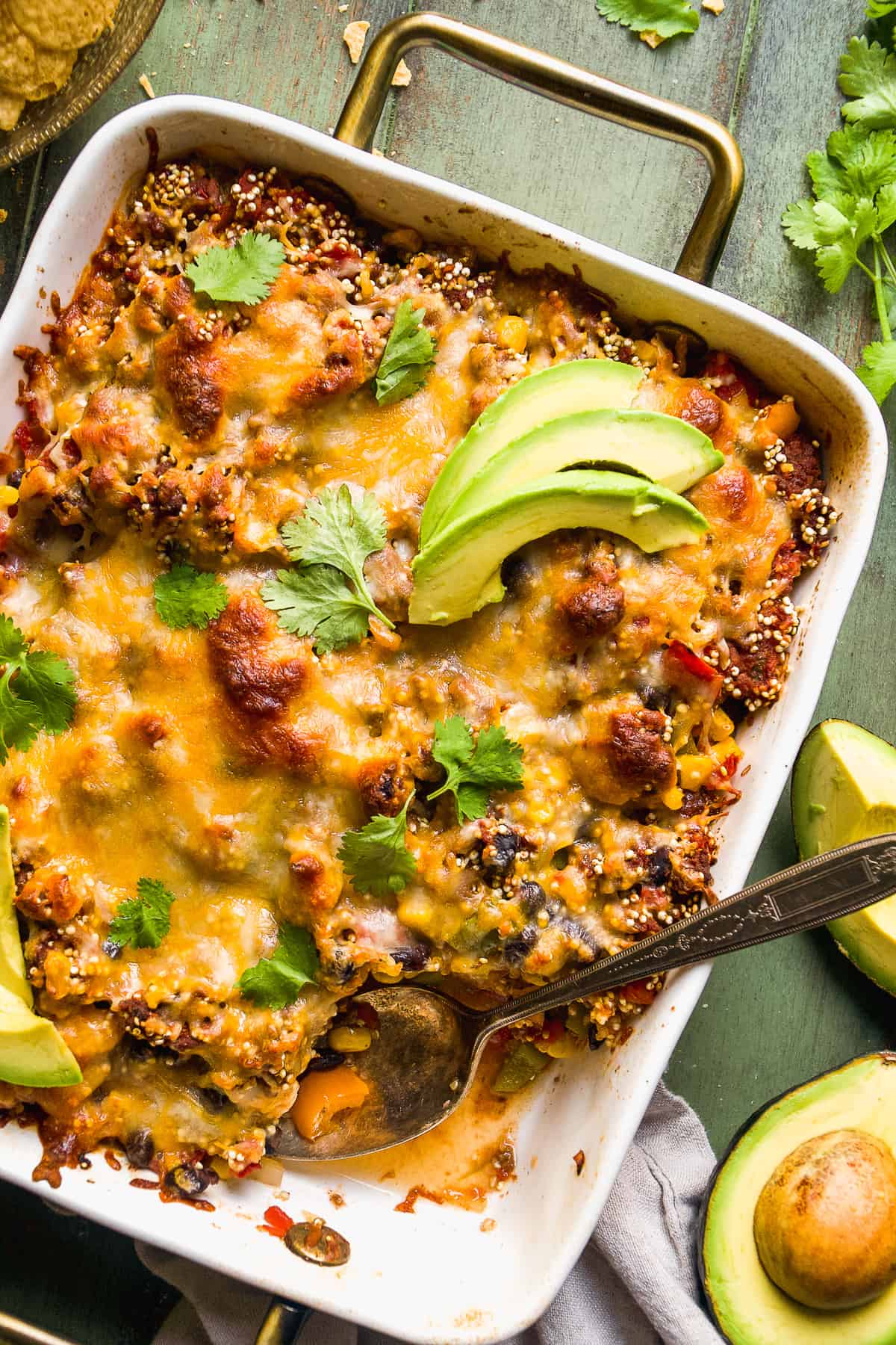 Taco casserole with a serving spoon and cheese on top.